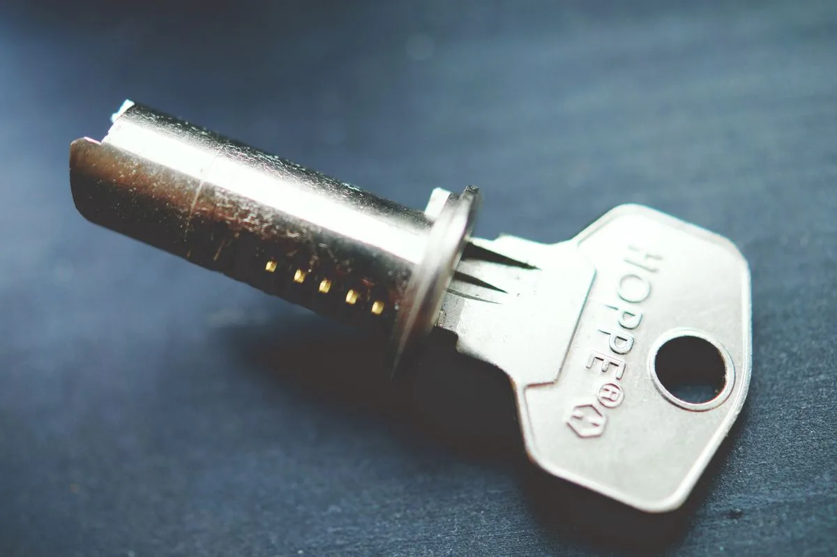 Close-up of a metal key and a lock cylinder on a dark surface