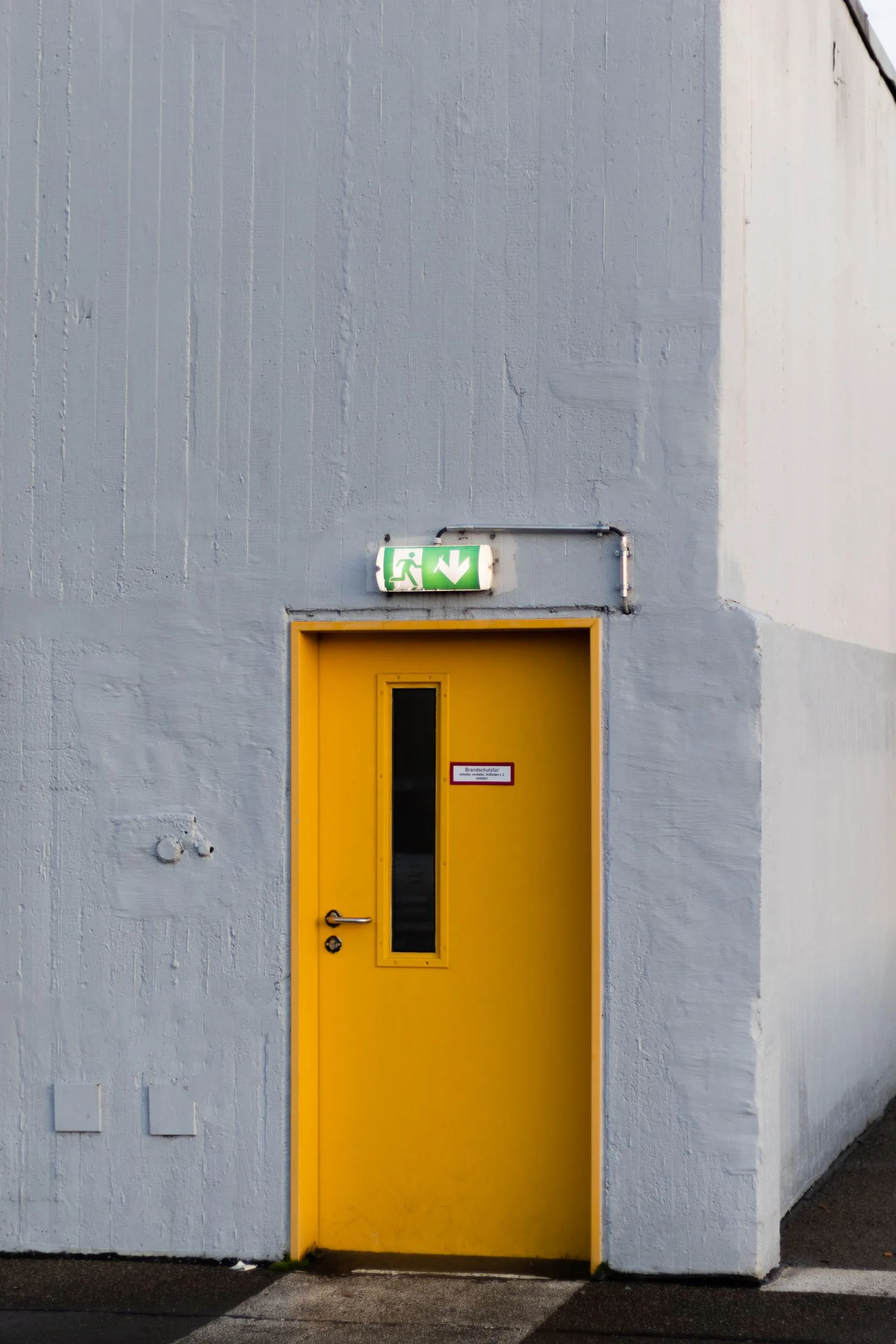Fire exit door in a concrete wall with an emergency exit sign above it