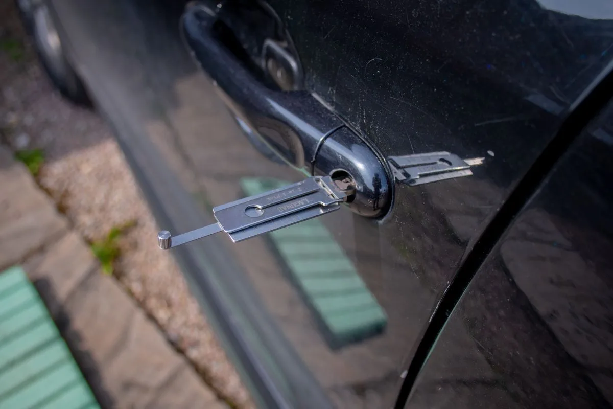 A locksmith tool inserted into a car door lock