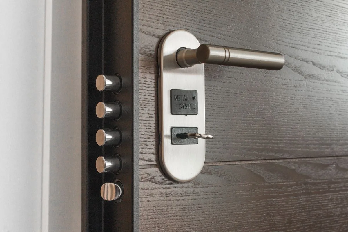 Metal door handle and lock with a key inserted in the cylinder