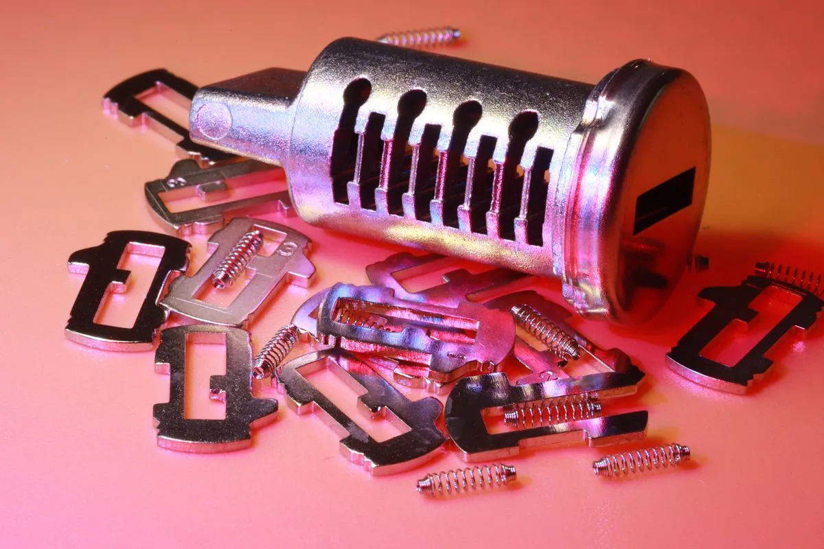 Disassembled lock cylinder with its pins, springs and plug laid out, the parts repinned in a master key system