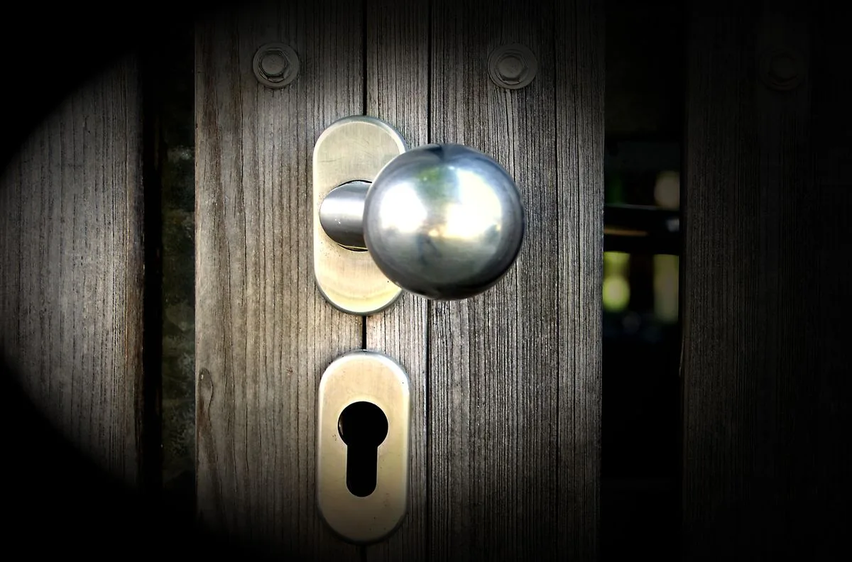 Close-up of a metal doorknob and keyhole on a wooden gate