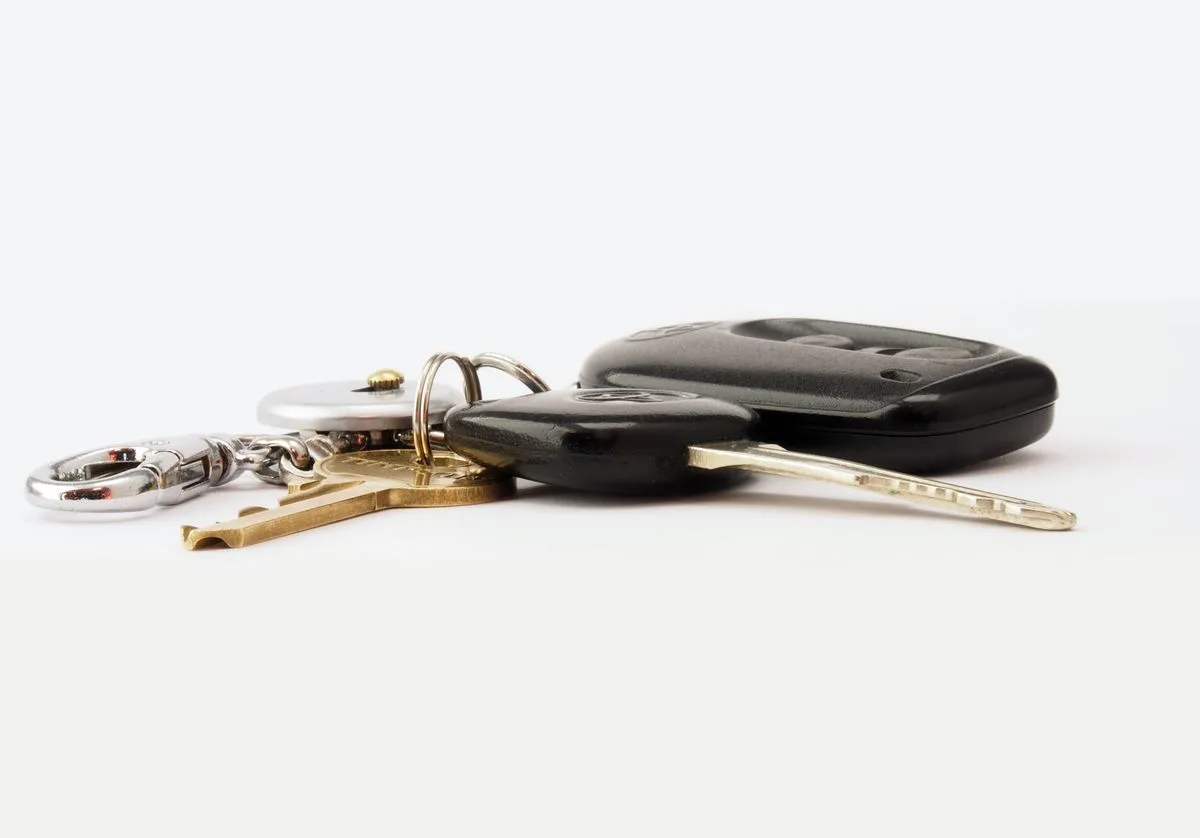 A set of car keys with a key fob and keychain on a white surface