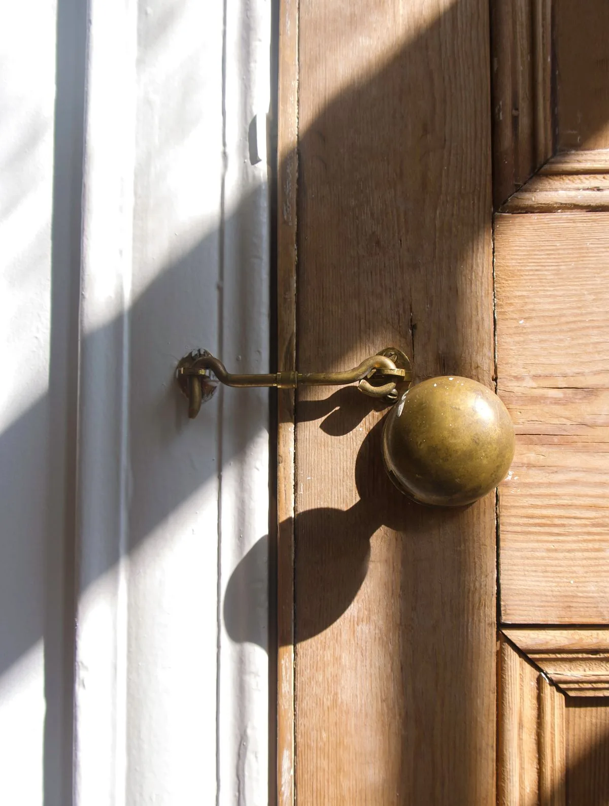 A brass door knob and latch on a wooden door